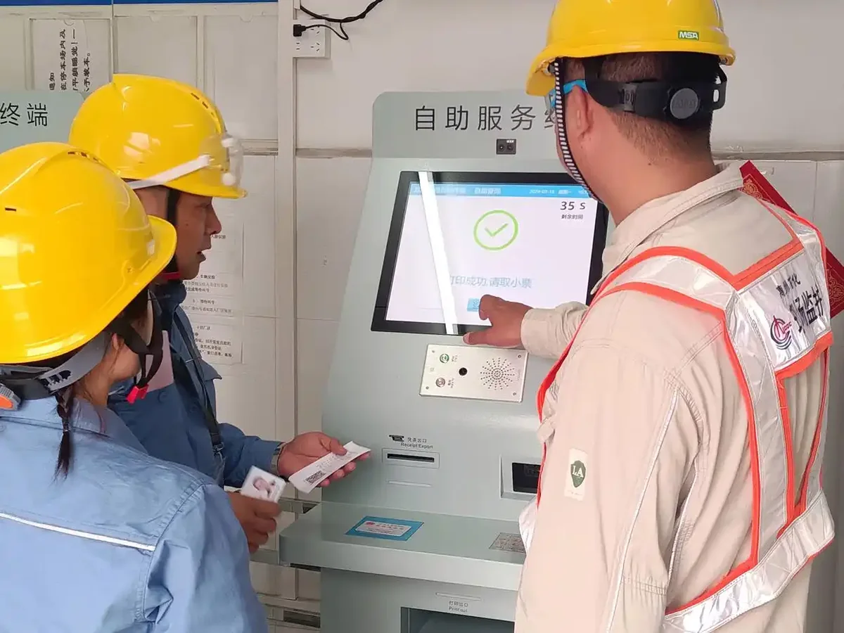 An operator helps a driver print a loading QR code at the self-service terminal. Photo: He Xiaozhong